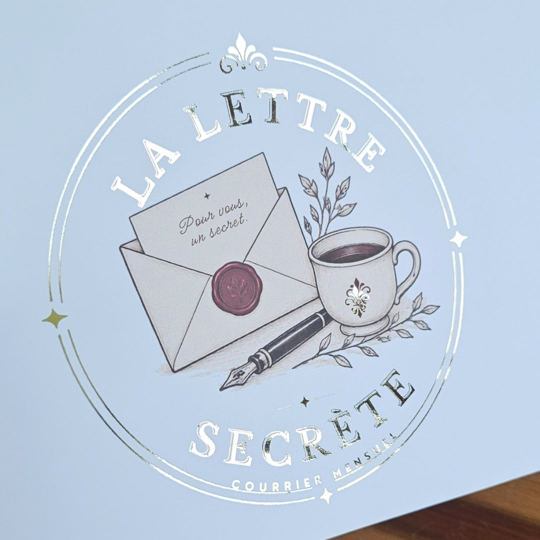 Logo La Lettre Secrète imprimé en dorure argentée sur un emballage bleu pâle, style élégant et artisanal