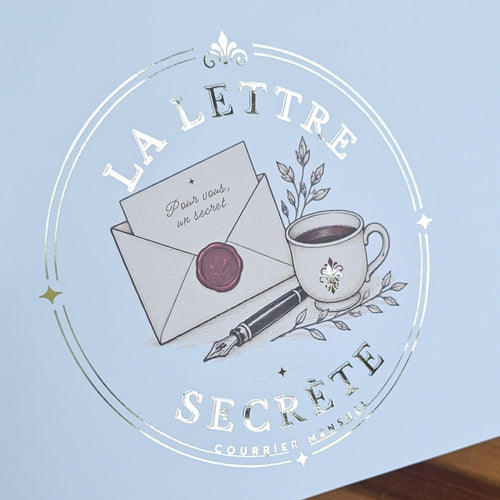 Logo La Lettre Secrète imprimé en dorure argentée sur un emballage bleu pâle, style élégant et artisanal